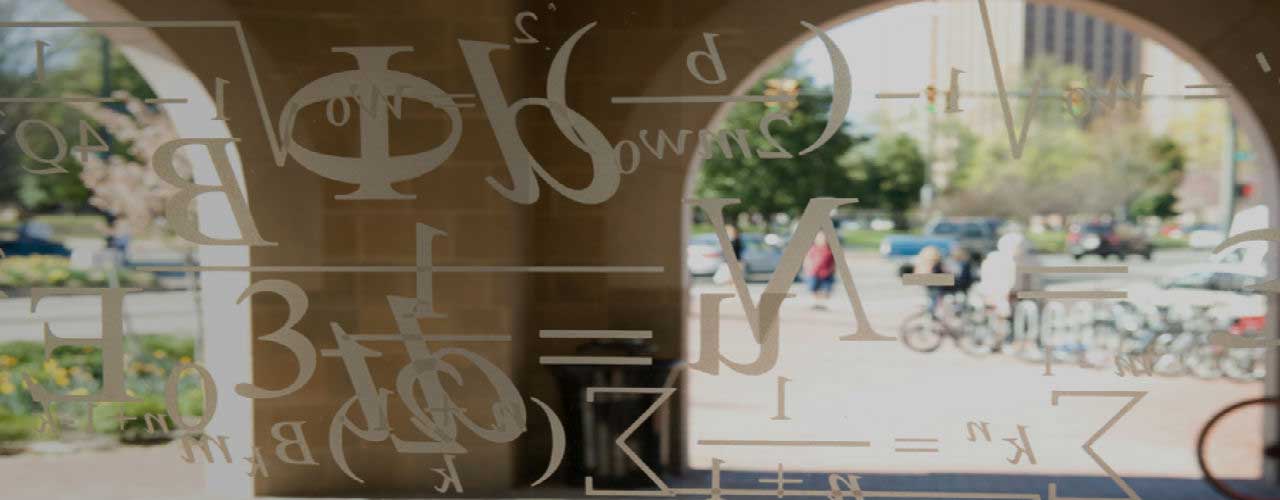 statistical equations etched on a window overlooking a college campus